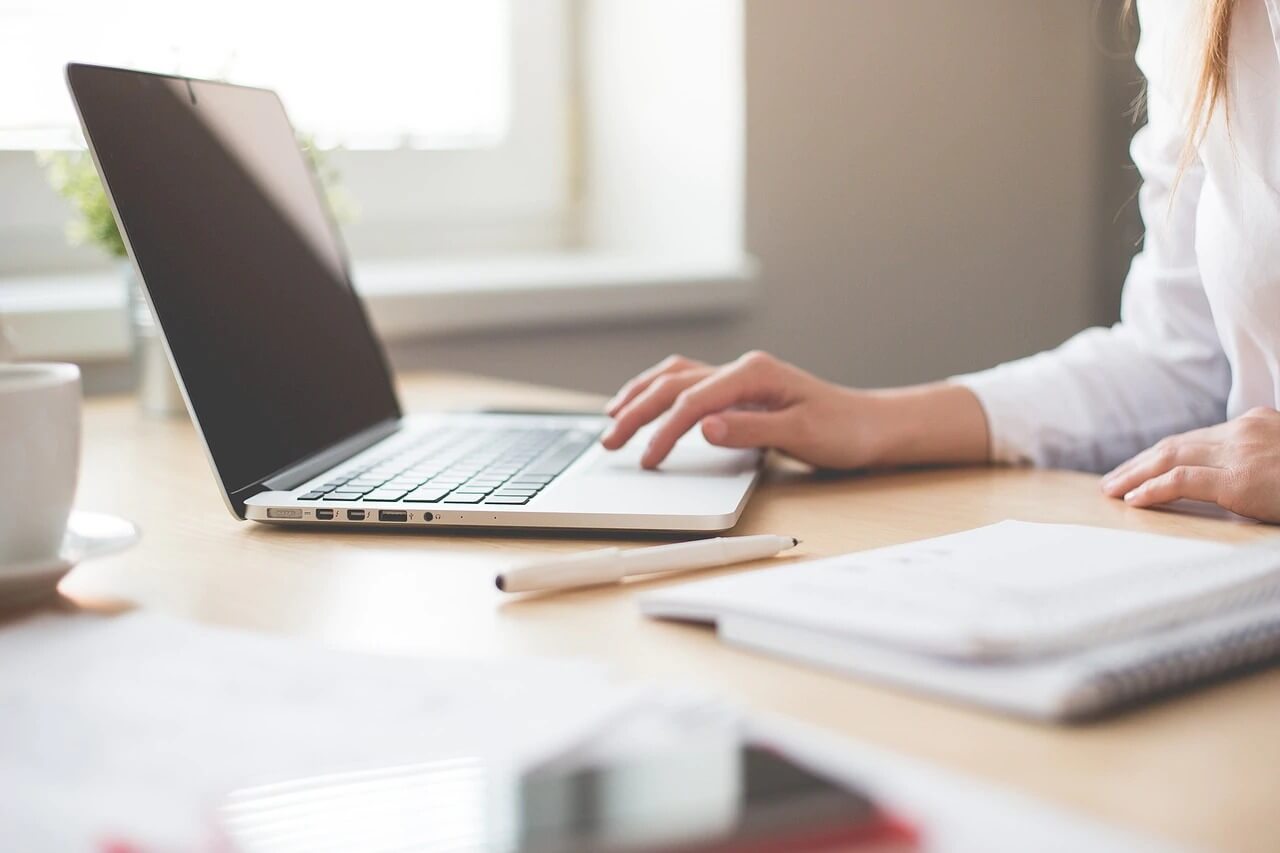 A person sitting at a table using a laptop computer