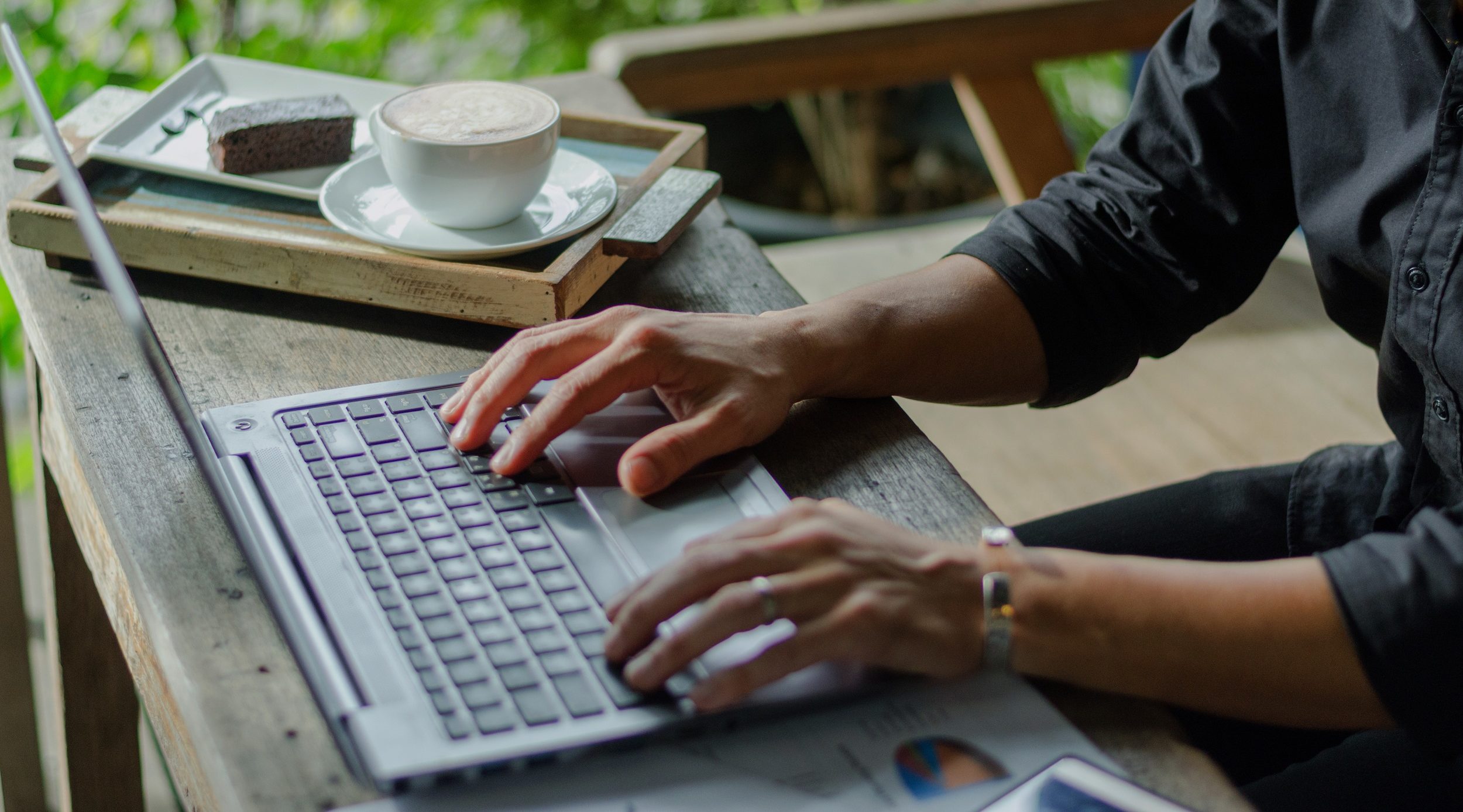 A person using a laptop computer sitting on top of a table